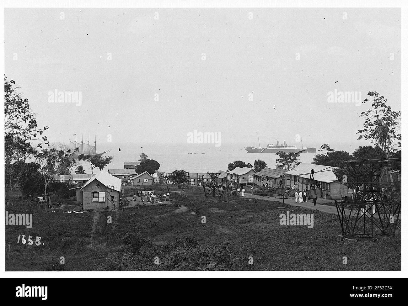 La Brea, Trinidad und Tobago. Passagierdampfer Moltke vor der Küste. Einheimische und Touristen vor den Häusern; rechts im Bild Industriebahn für Asphalttransport vom Pitch Lake, der zur Landebrücke führt Stockfoto