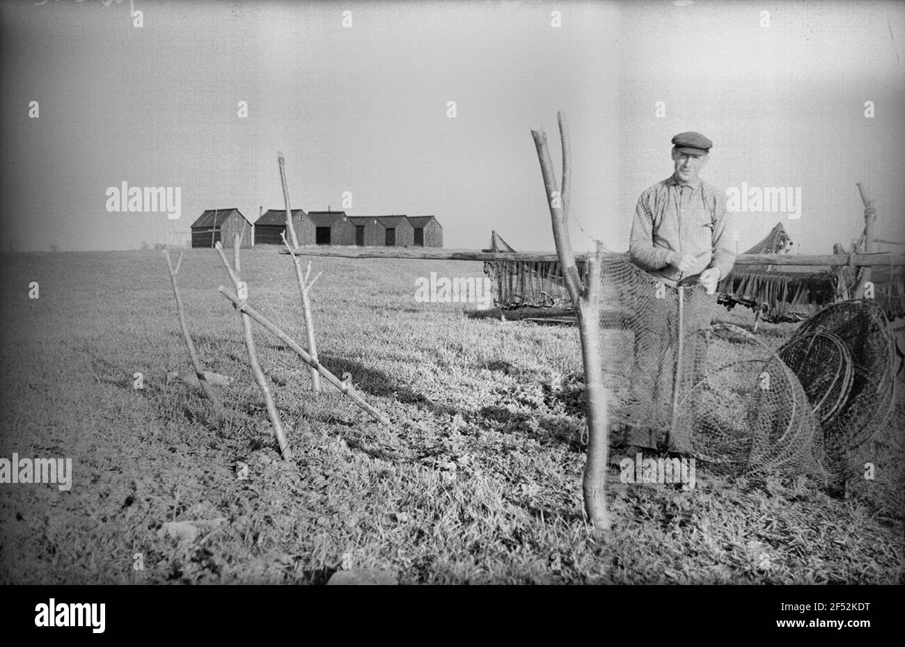 M? Hlberg. Ein Fischer verbessert ein Garn. Im Hintergrund sechs Fischerstile Mühlberg. Ein Fischer verbessert ein Garn. Im Hintergrund sechs Angelstile Stockfoto