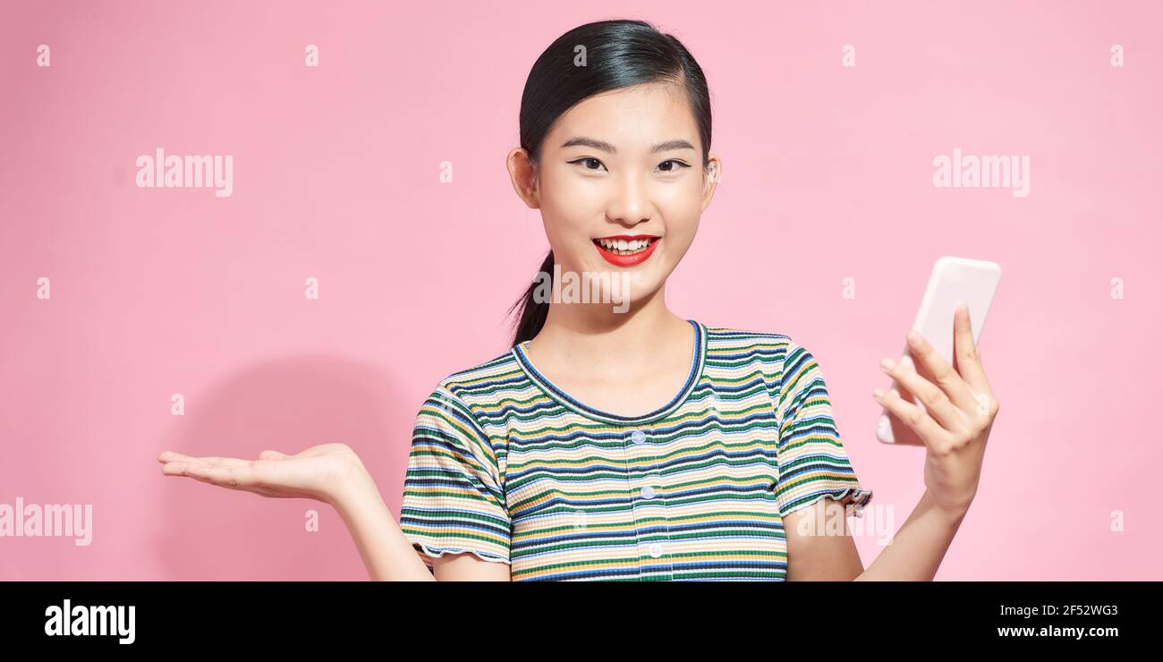 Glücklich asiatische Frau Gefühl Glück und stehend halten Smartphone andere Hand auf rosa Hintergrund öffnen Stockfoto