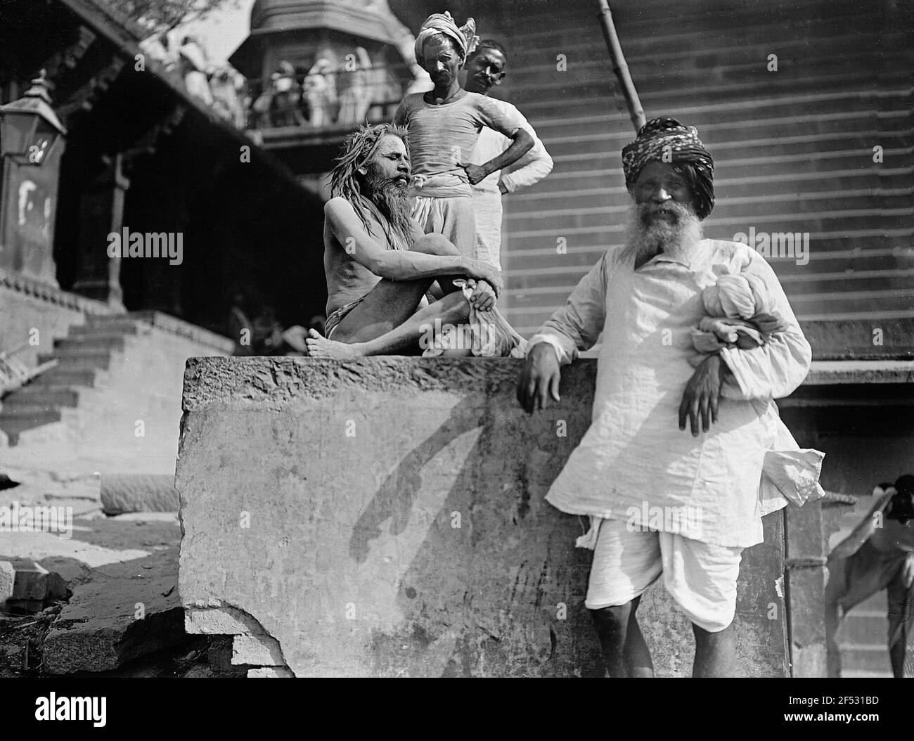 Varanasi (Benares), Indien. Heiliger Mann (Sadhu) sitzt auf einem Stein vor dem Tempeleingang Varanasi (Benares), Indien. Heiliger Mann (Sadhu) sitzt auf einem Stein vor dem Tempeleingang Stockfoto