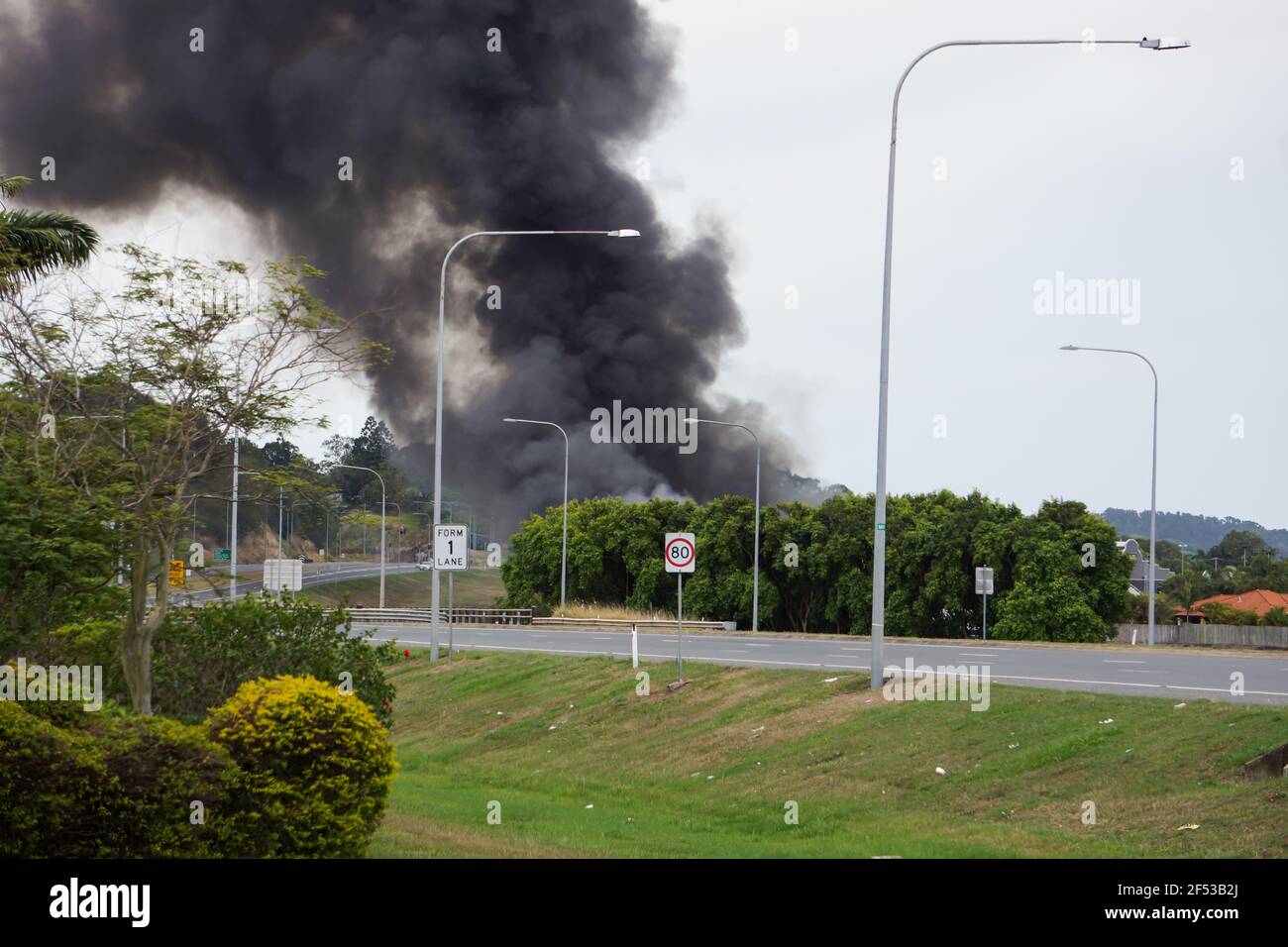 Eine große schwarze Rauchwolke aus einem Gebäude, das sich in der Nähe der Autobahn befindet und in Brand ist. Stockfoto