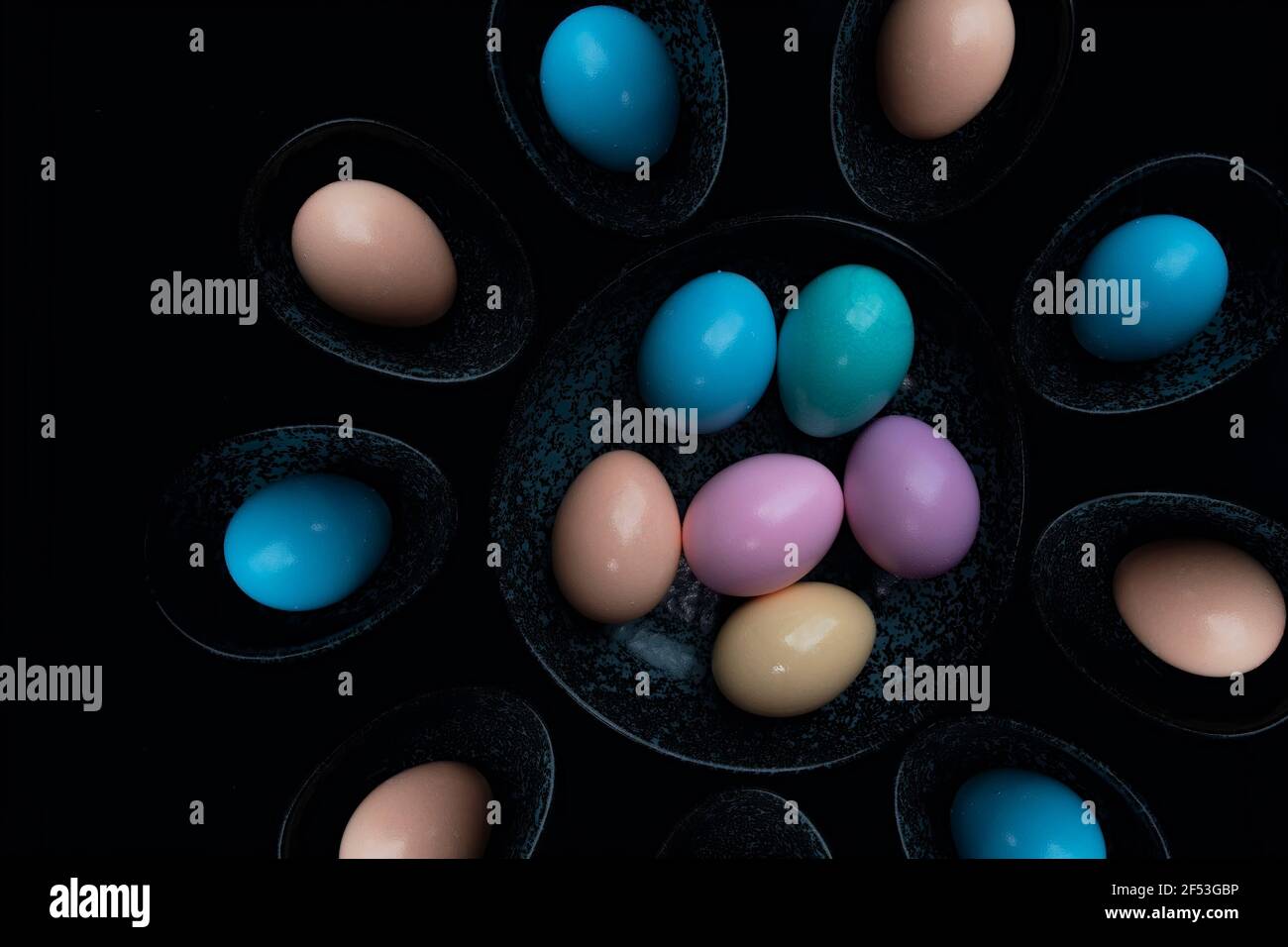 Ansicht pastellfarbene Ostereier auf einer dunklen Granitplatte vor schwarzem Hintergrund. Stockfoto