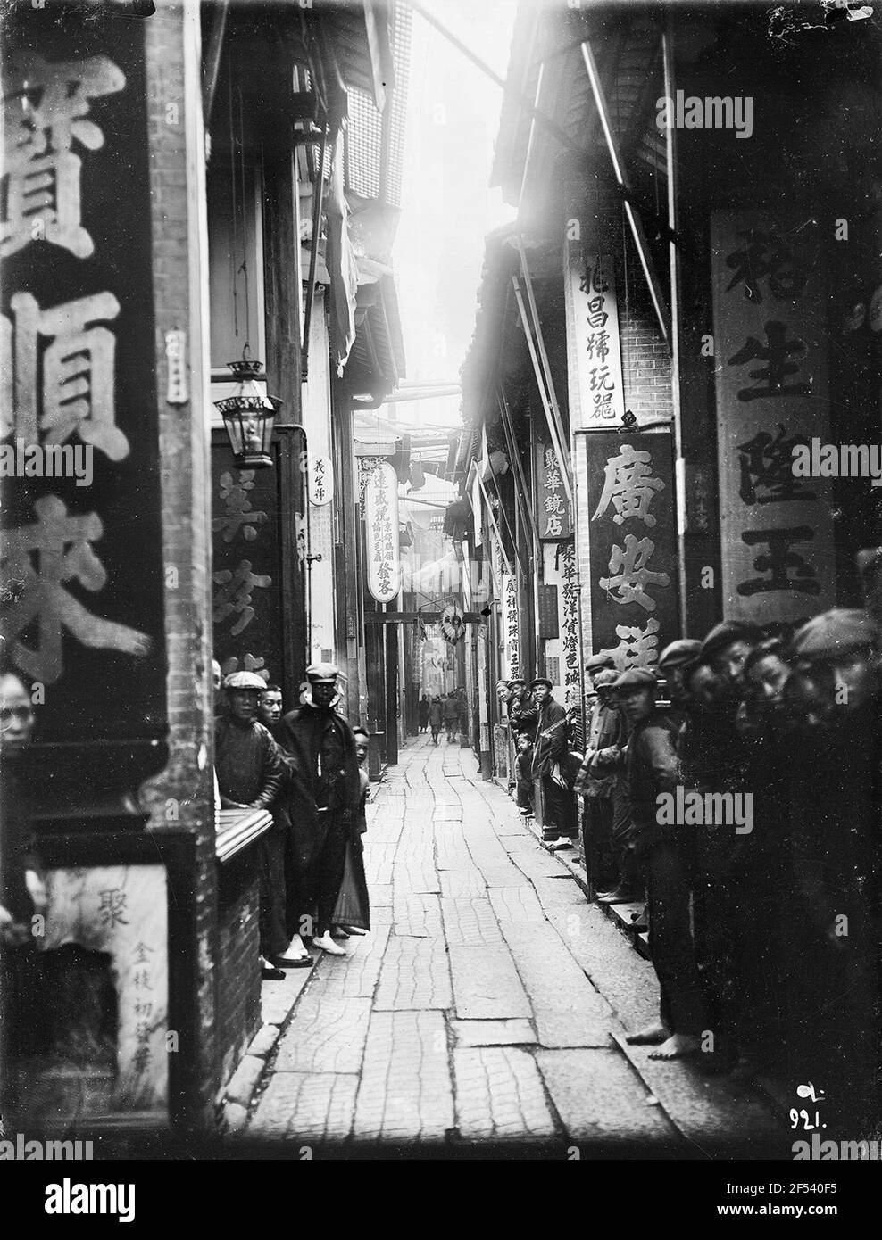 Hong Kong Altstadt. Gasse mit chinesischen Schriftzeichen und Spruchbändern im chinesischen Viertel. Neugierige Einheimische stehen am Rand und schauen auf die Kamera Stockfoto