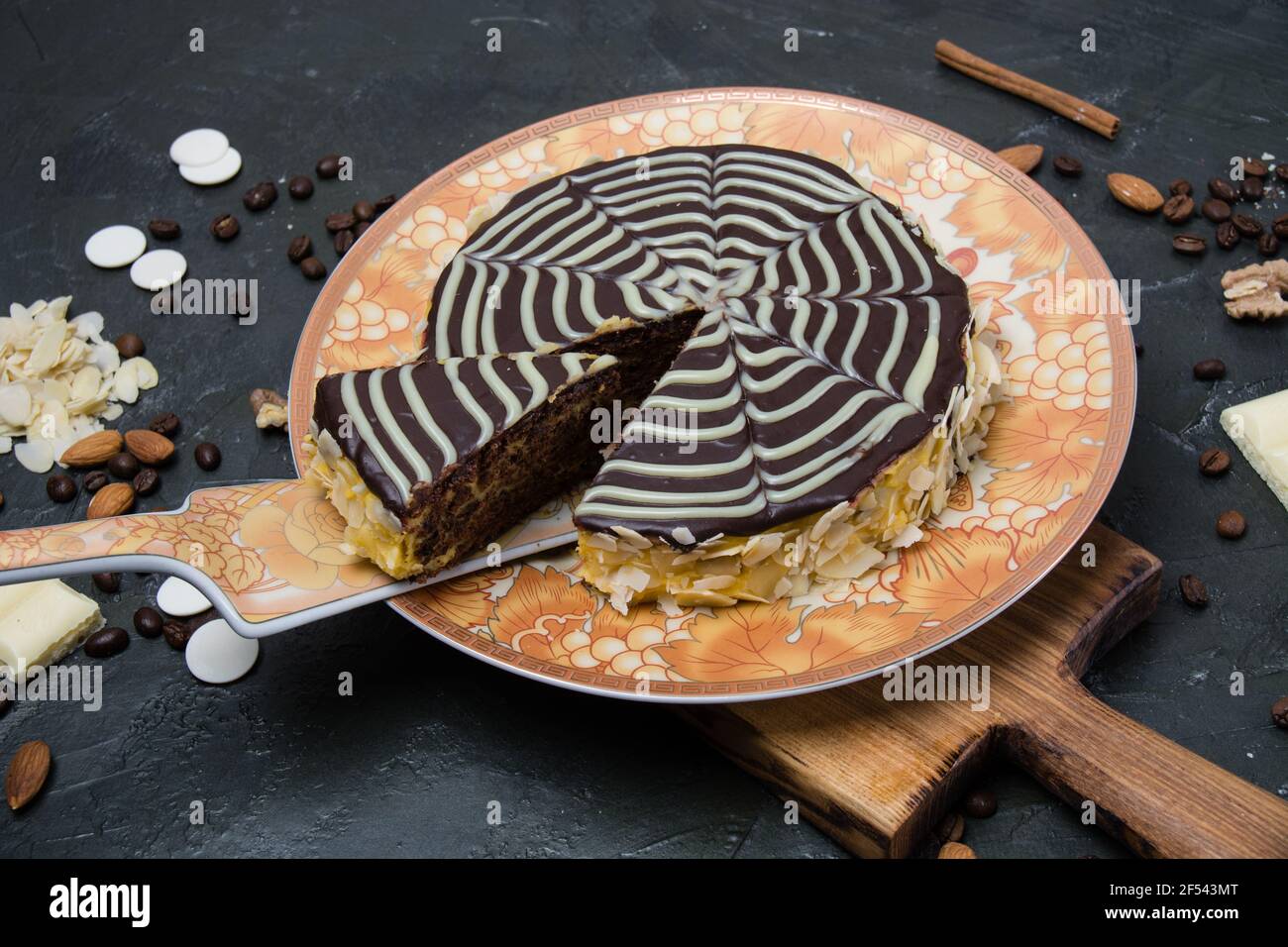Schokolade in Scheiben geschnitten esterhazy Kuchen mit Sahne, Zuckerguss, Nüsse, Zimt und Mandeln Nahaufnahme von oben auf einem orange-braunen Teller, auf einem hölzernen Wildschwein Stockfoto