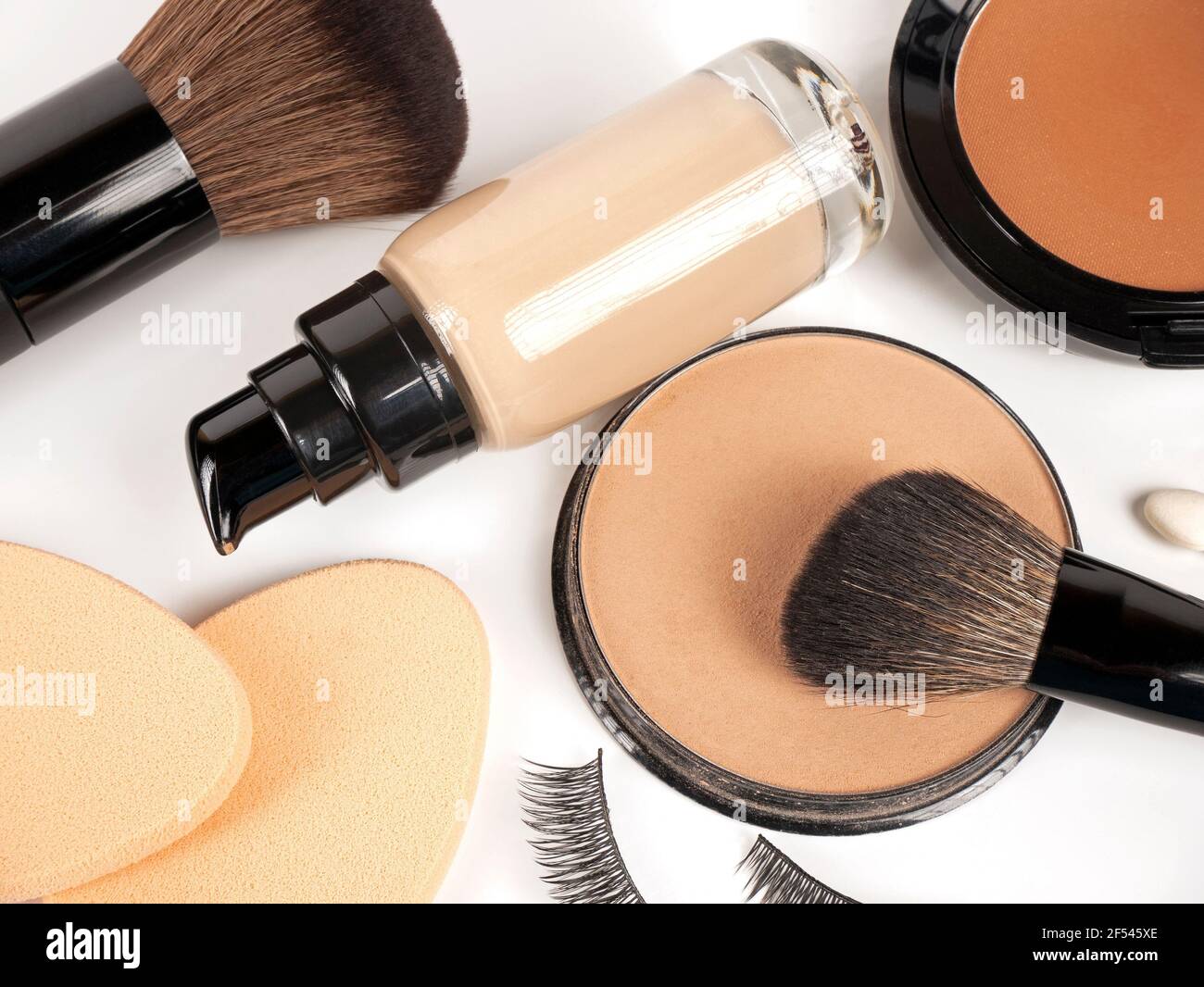 Foundation, Pulver, Concealer, Make-up Pinsel, Make-up Schwämme, Falsche Wimpern auf weißem Hintergrund Stockfoto