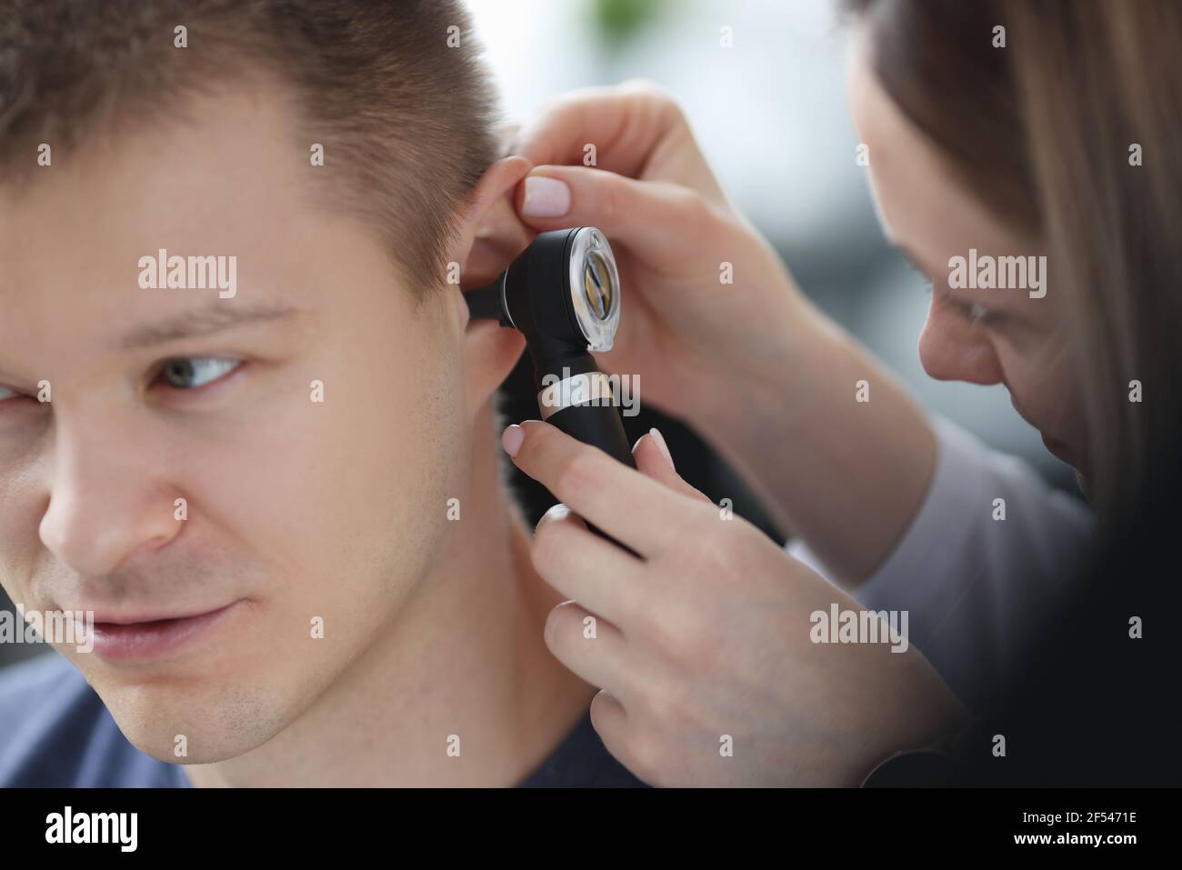 Otorhinolaryngologe, der das Ohr des kranken Mannes mit Otoskop-Nahaufnahme untersucht Stockfoto