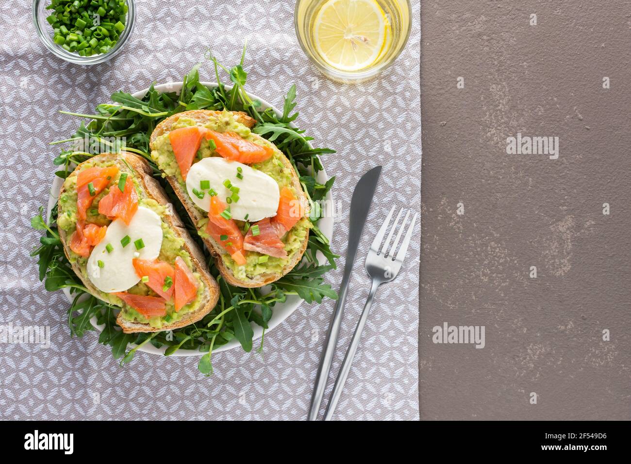 Leckeres herzhaftes Frühstück, Sandwiches mit Avocado-Paste, Lachs und Mozzarella auf einem Teller mit Rucola und Erbsensprossen Stockfoto