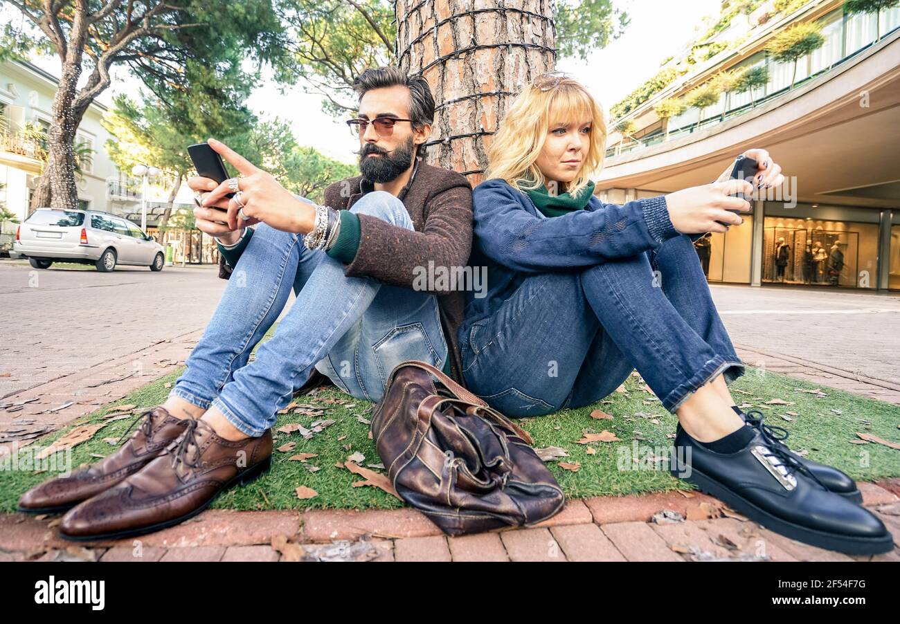 Hipster Millennial Paar in Desinteresse Moment mit Smartphone - Apathie Konzept über Traurigkeit und Isolation mittels Handy Stockfoto