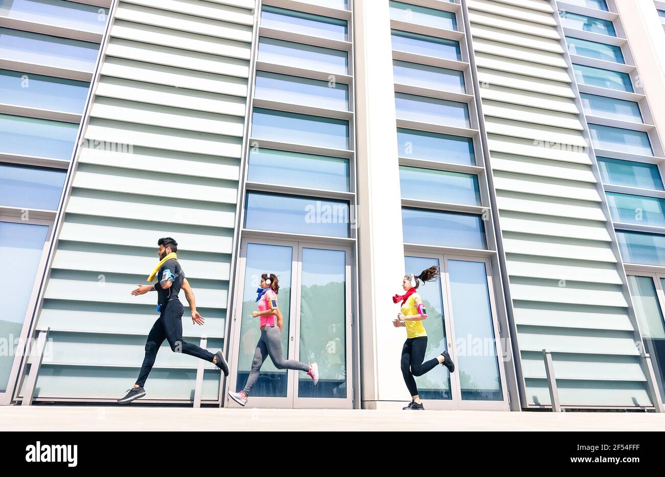 Gruppe von jungen Menschen laufen in modernen städtischen Bereich - Fitness-Mädchen laufen mit männlichen Trainer Trainer in der Stadt - Sportkonzept mit Freunden Joggen Stockfoto