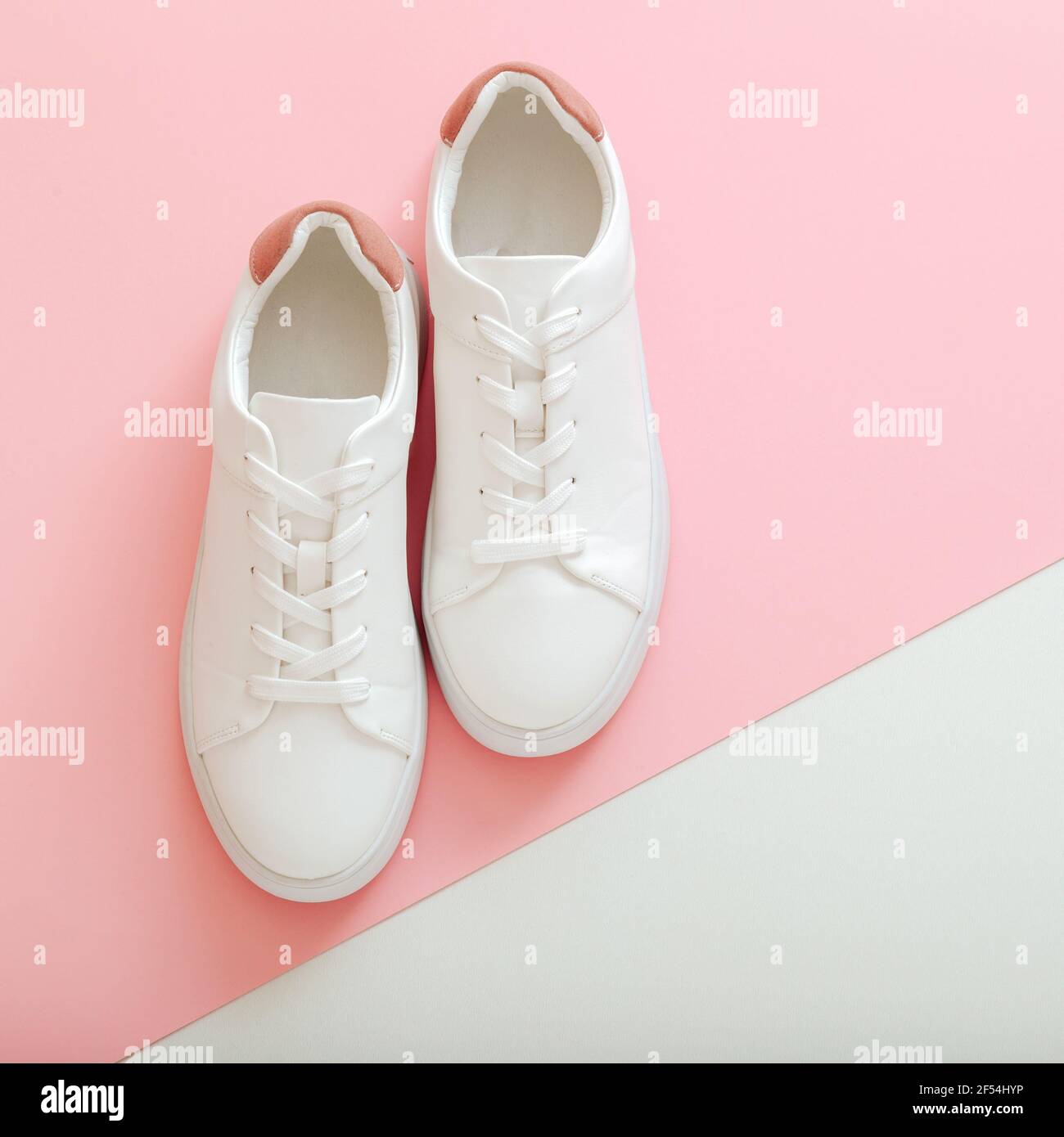 Weiße Sneakers, weibliche weiße Lederschuhe mit Schnürsenkeln auf rosa  Hintergrund. Paar stilvolle Sneaker bequeme Sportswear Hipster Damenschuhe.  Oben Stockfotografie - Alamy