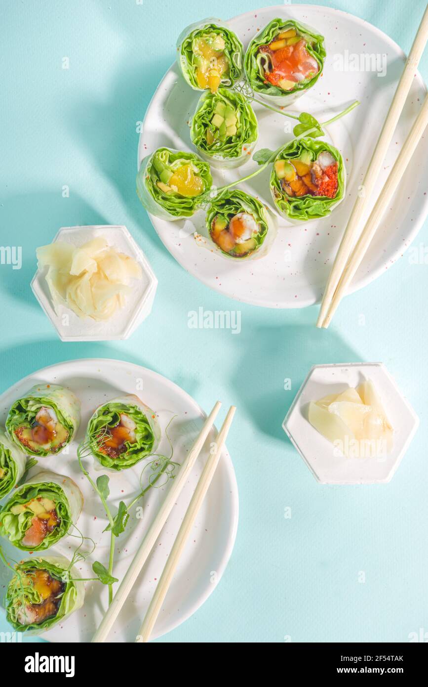 Mediterrane, nordische und Keto Diät-Konzept. Sushi ohne Reis, Diätkost mit Meeresfrüchten, Gemüse. Trendige asiatische Sushi-Stil Frühlingsrollen auf blau Mo Stockfoto