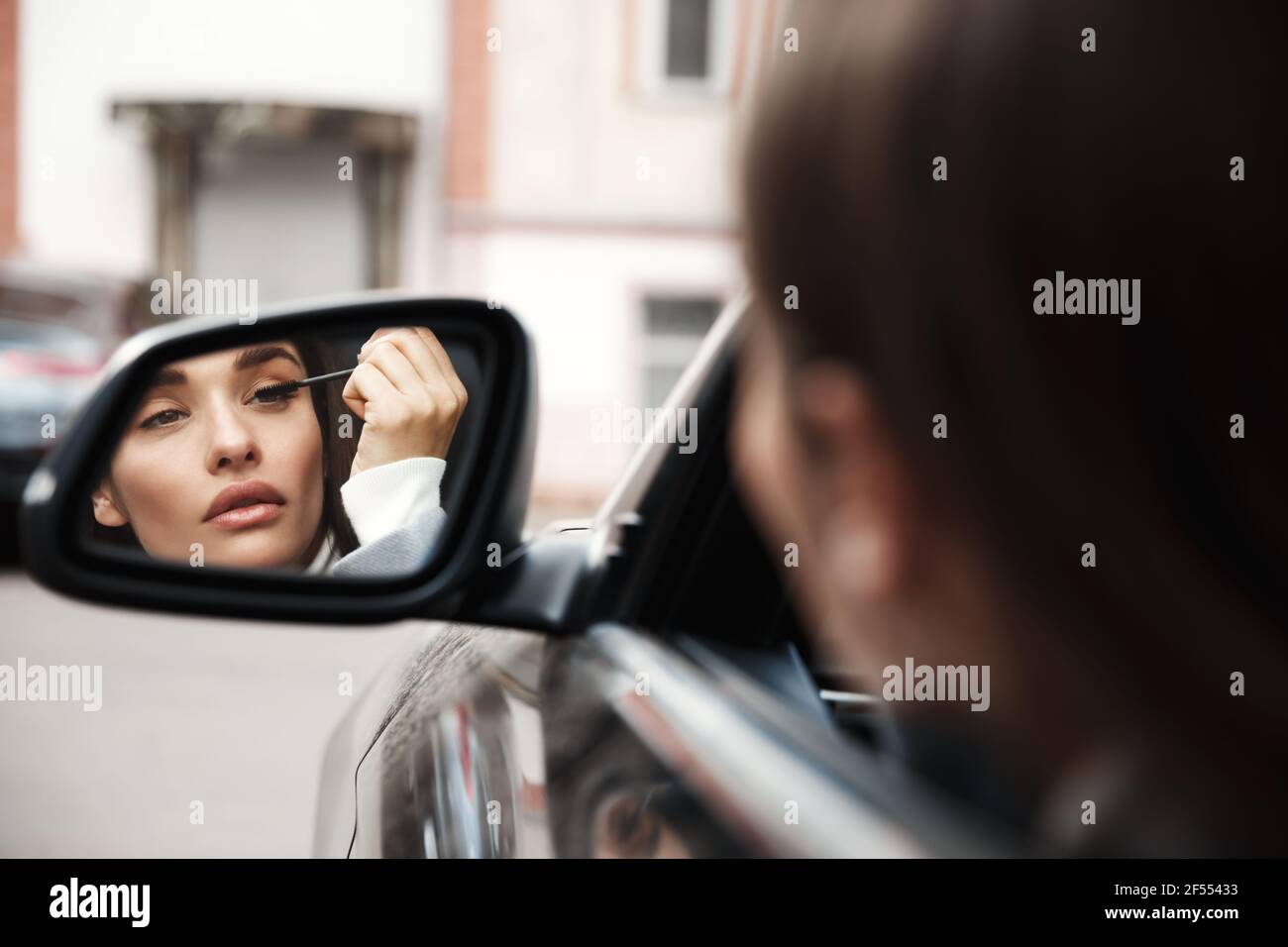 Geschäftsfrau Fahrer Blick auf Rückspiegel, während im Auto sitzen Und Wimperntusche auftragen Stockfoto