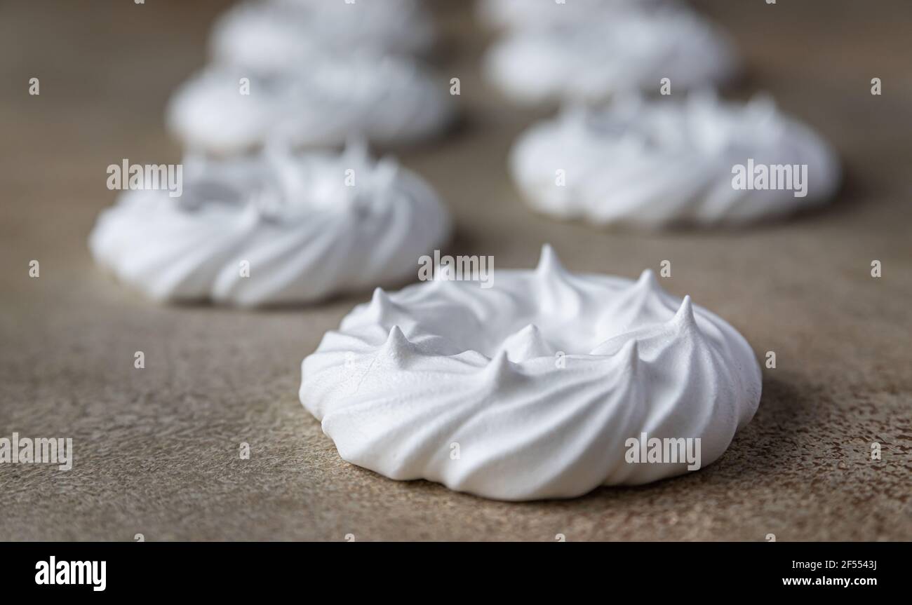 Leere Baiser Nester, heller Steinhintergrund. Konzept für einen leckeren süßen Nachtisch. Selektiver Fokus. Stockfoto