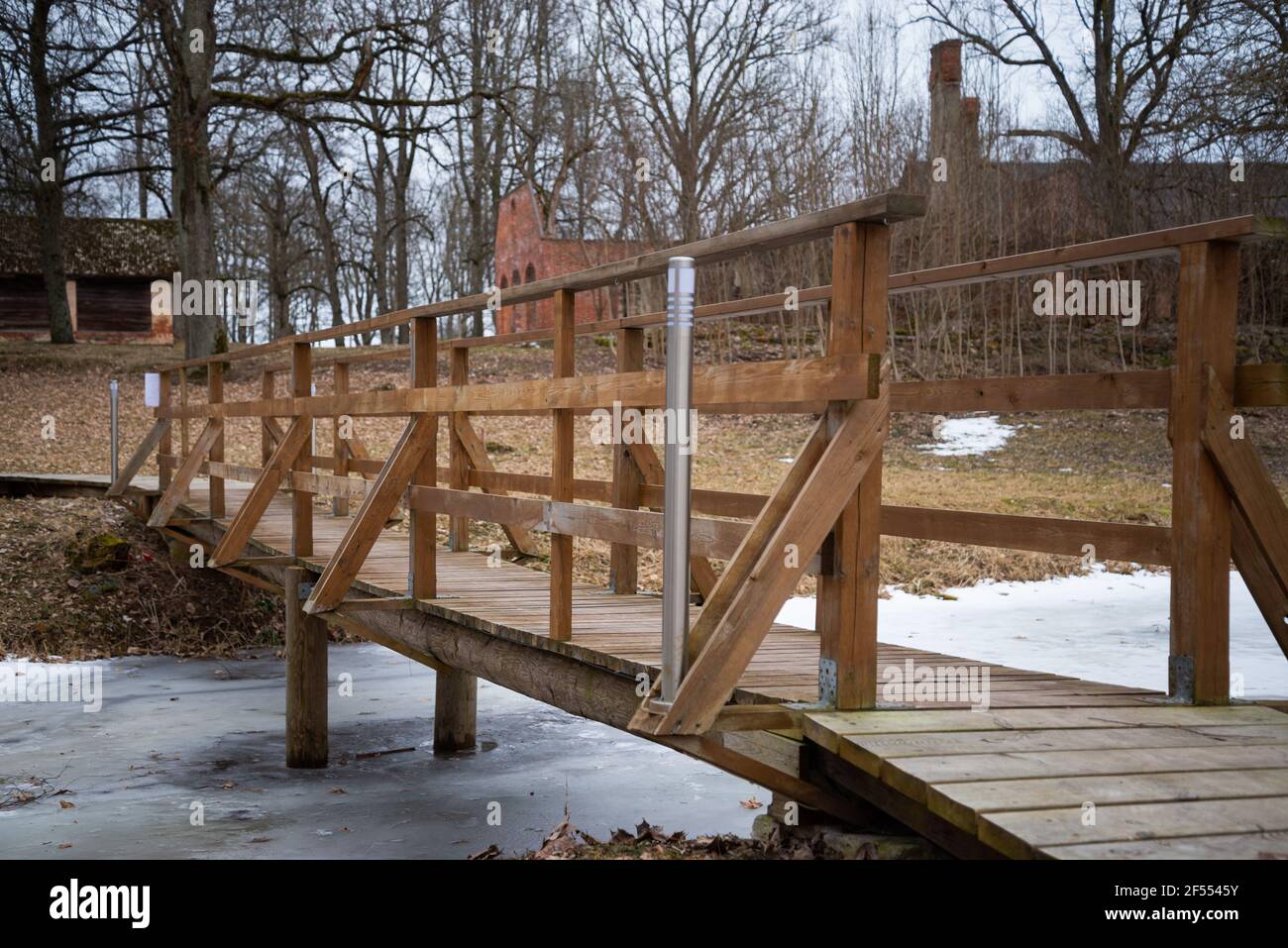 Holzbrücke über einen gefrorenen Fluss im Park mit Leuchtlante Stockfoto