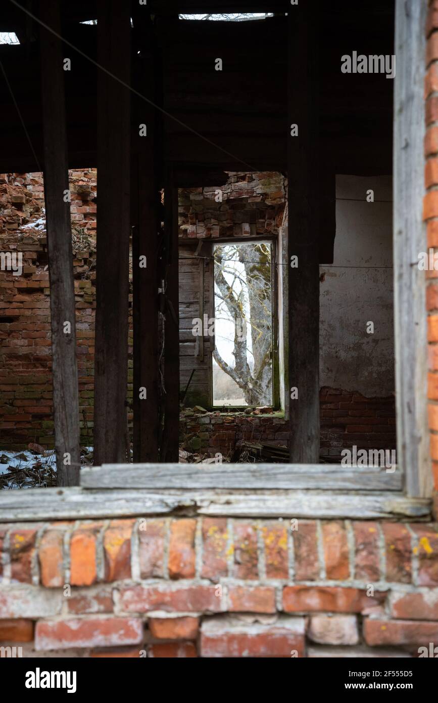 Verlassene eingestürzte rote Backsteingebäude Innenraum durch einen alten Holzfensterrahmen. Der Blick führt Sie auf das gegenüberliegende Fenster, durch das Sie s können Stockfoto