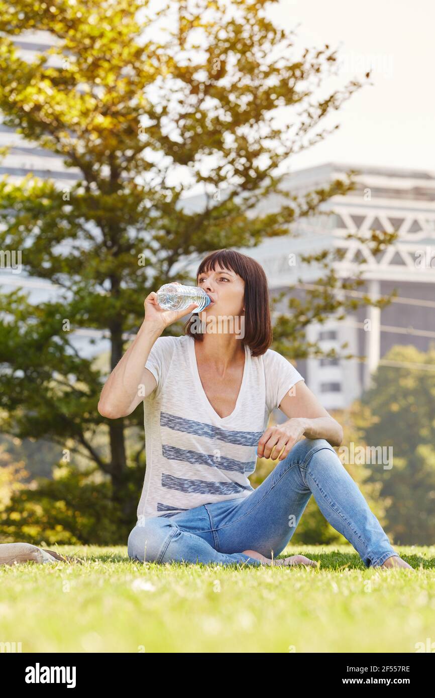 Ganzkörperportrait einer Frau, die barfuß im Wasser sitzt Gras Stockfoto