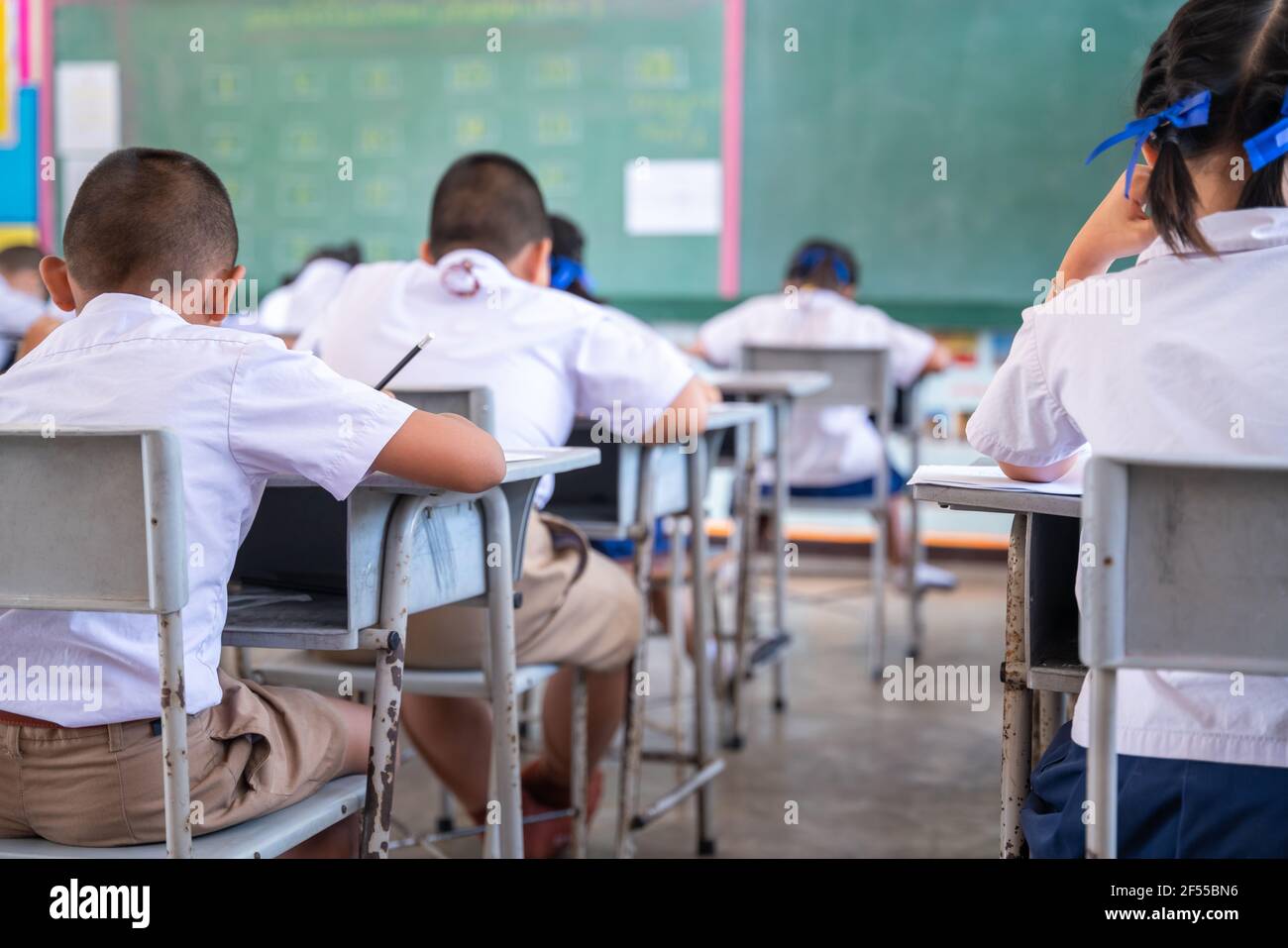 Nahaufnahme des Schreibstests in der Prüfung mit hinter Kind asiatische Schüler Gruppe konzentrieren sich in der Grundschule, Abschlussprüfung Schreibtisch im Klassenzimmer mit Thai s Stockfoto