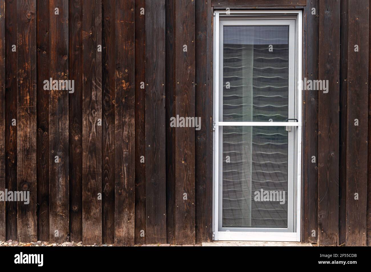Alte Holzfassade eines Wohngebäudes mit einem neuen Fliegenschirmtür in die Terrassentür eingebaut Stockfoto