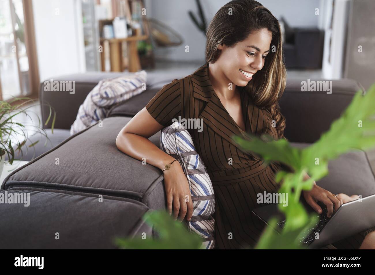 Charmante junge attraktive Frau sitzend Lounge-Zone, Co-Working-Raum liegend Couch halten Laptop Runden schauen zufrieden net-Buch Display lächelnd erfreut Stockfoto