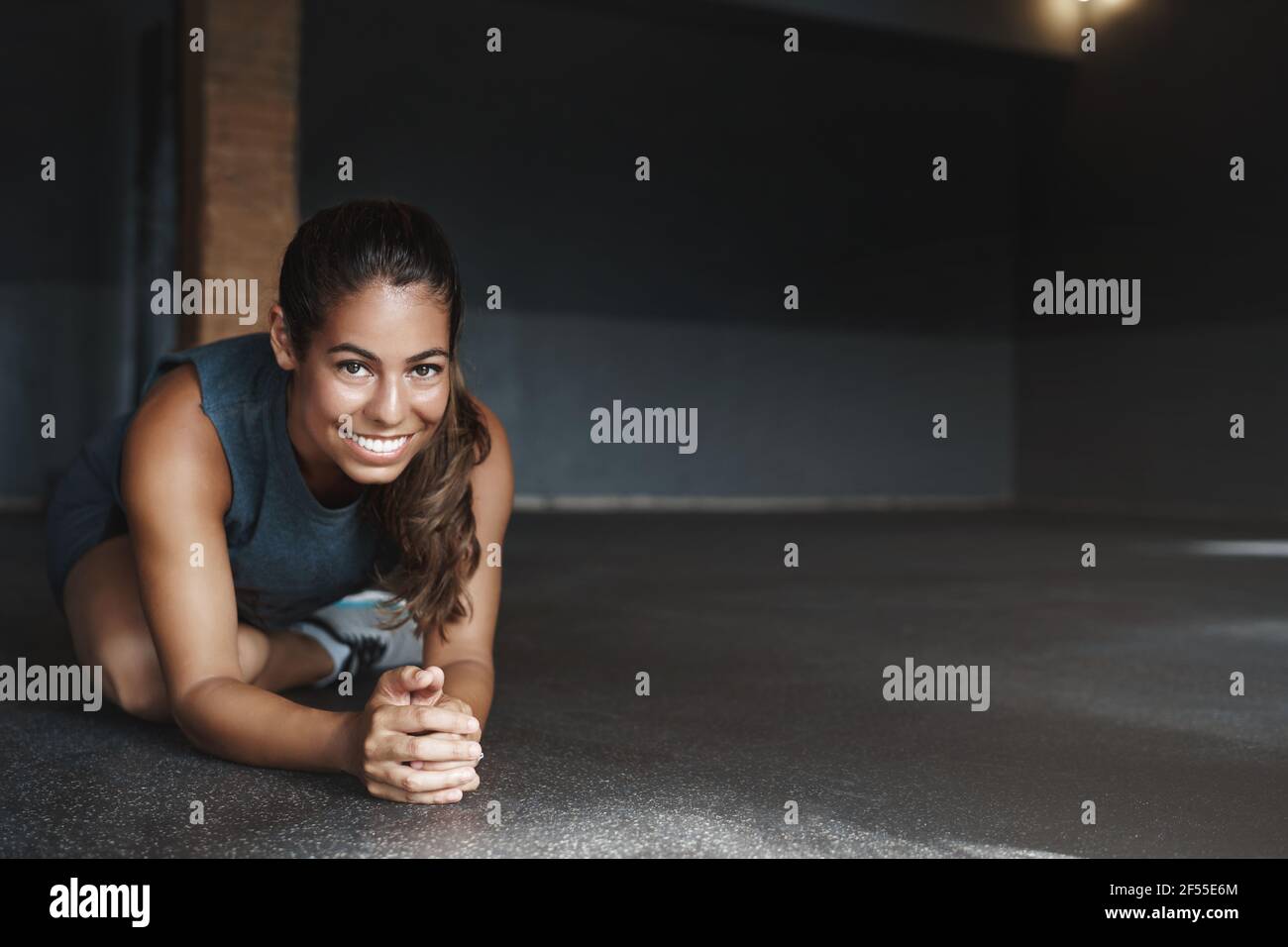 Attraktive hispanische Frau Stretching Körper, sitzen mit gekreuzten Bein, Halb-Plank, tun Fitness-Übungen, Training. Sportlerin Warm-up vor der Gruppe Stockfoto