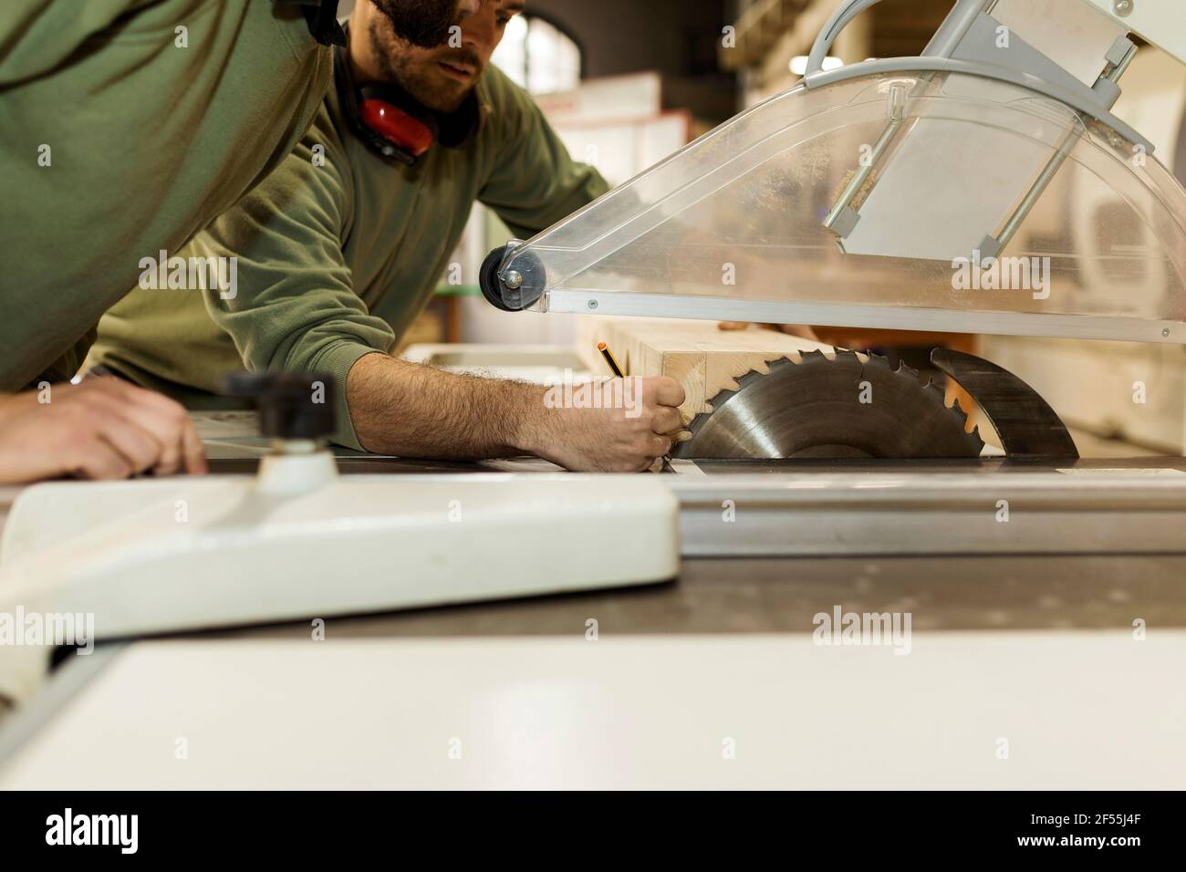 Tischlermänner, die in der Werkstatt an der Tischsäge arbeiten Stockfoto