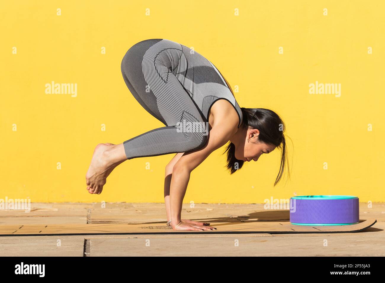 Starke Frau, die an der gelben Wand einen Handstand einnimmt Stockfoto