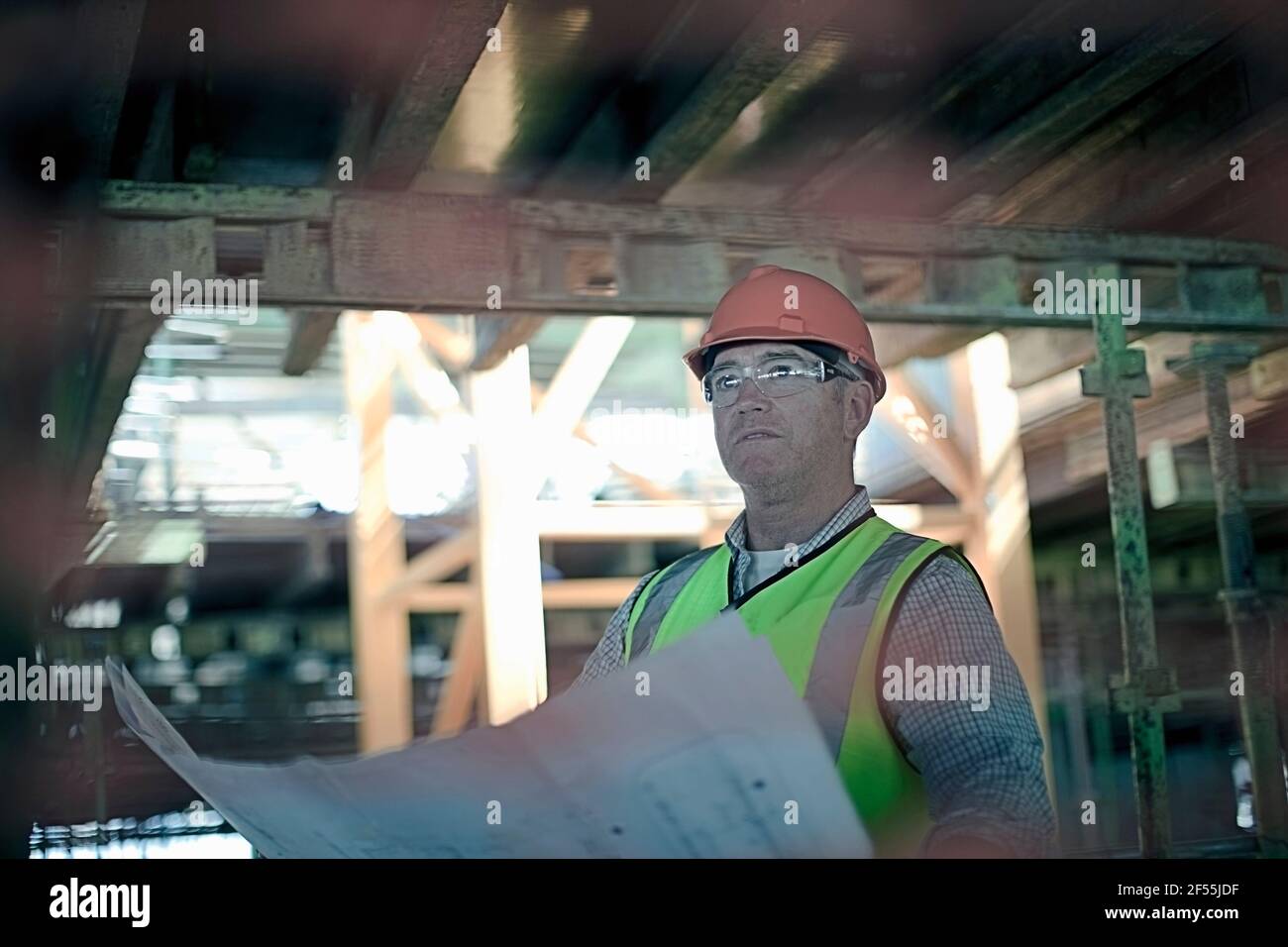 Reifer männlicher Bauarbeiter mit Bauplan in der Bauindustrie Stockfoto
