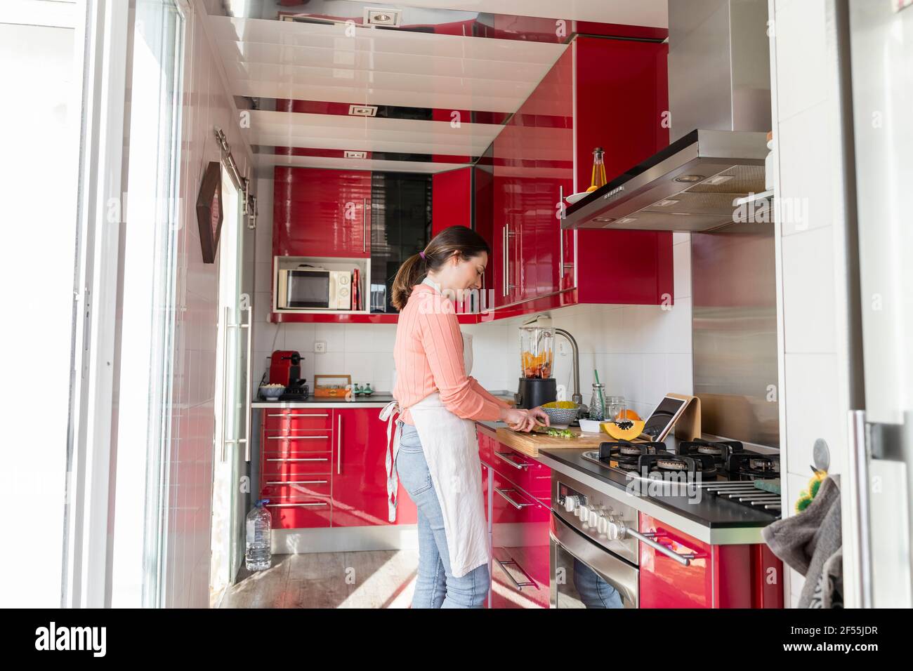 Junge Frau, die zu Hause in der Küche steht und Lebensmittel zubereitet Stockfoto
