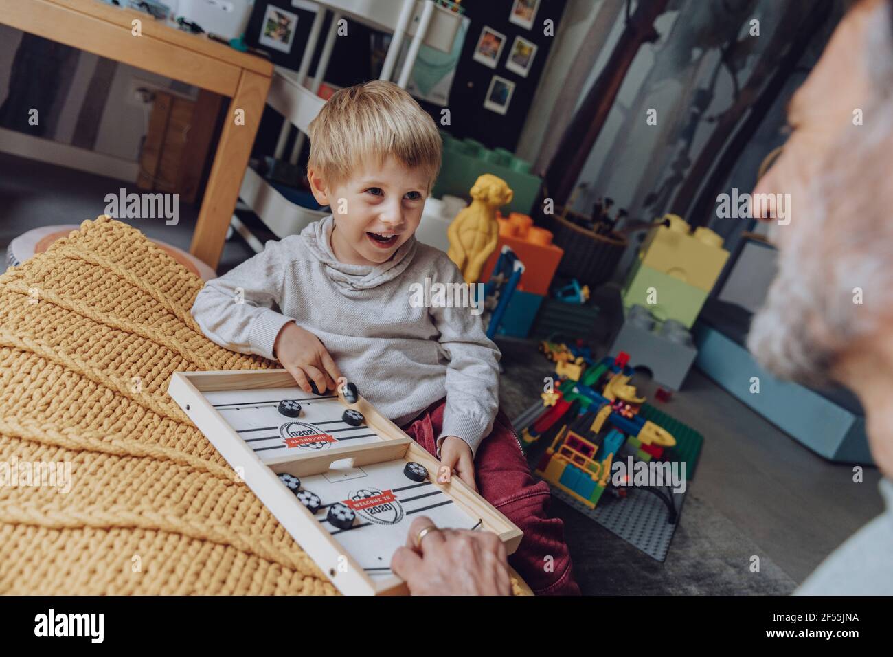 Fröhlicher Sohn, der Vater ansieht, während er Tischfußballbrett spielt Spiel im Schlafzimmer Stockfoto