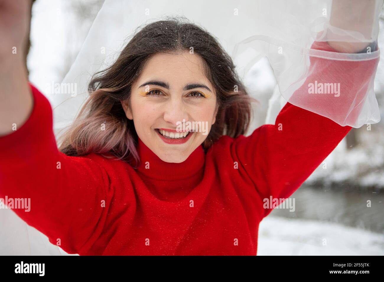 Schöne Frau mit erhobenen Armen hält weißen Tuch im Winter Stockfoto