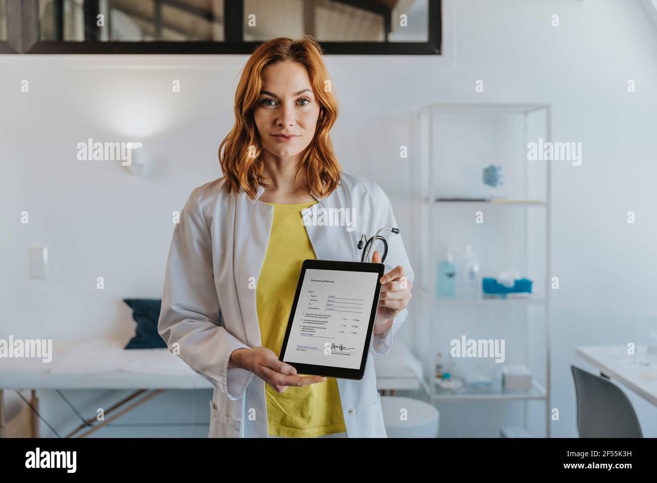 Hausarzt zeigt digitale Tablette, während er in der Klinik steht Stockfoto