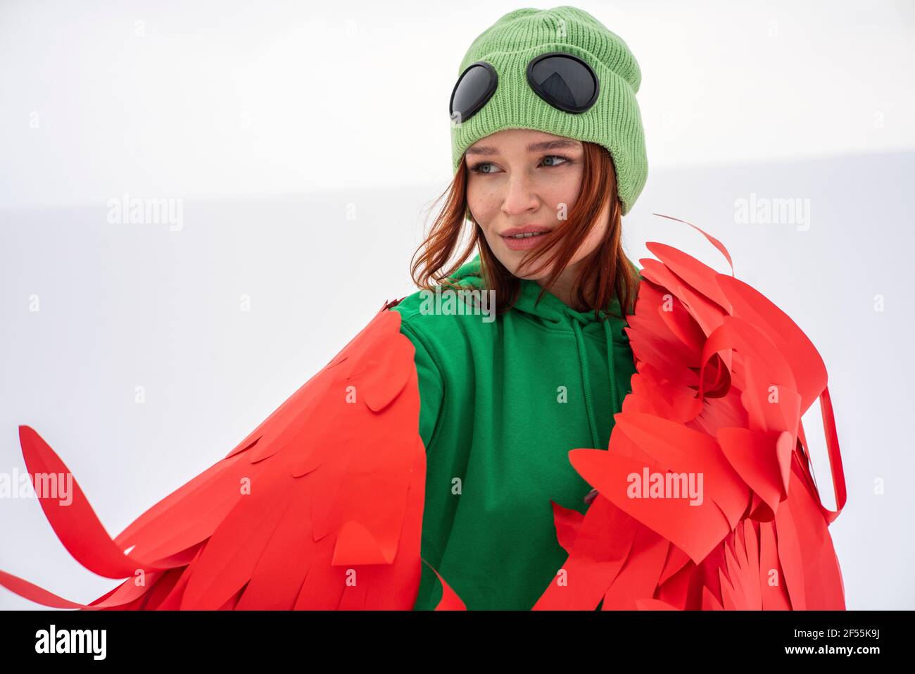 Lächelnde Frau mit roten Flügeln, die zum Himmel hinwegschauen Stockfoto