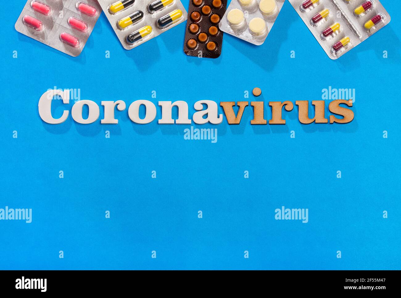 Coronavirus Phrase Text auf blauem Hintergrund mit Medikamenten. Stockfoto