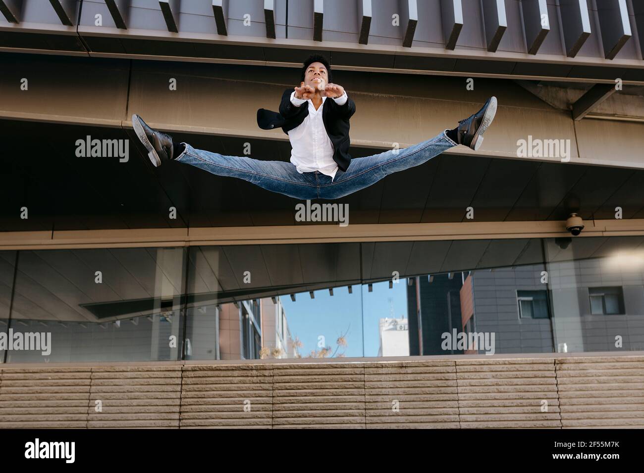 Männlicher Unternehmer, der während der Splits in der Luft tanzt Stockfoto