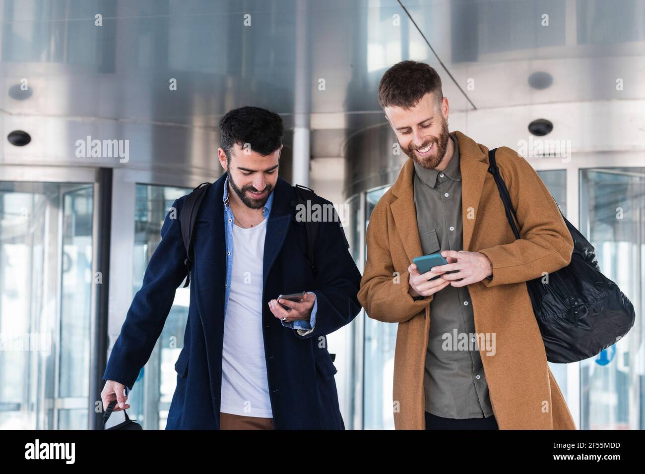 Geschäftspartner, die Mobiltelefone nutzen, während sie mit dem Sack gegeneinander stehen Gebäude Stockfoto