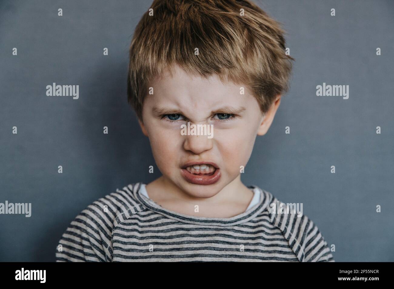 Wütend Junge Grimacing über grauen Hintergrund Stockfoto