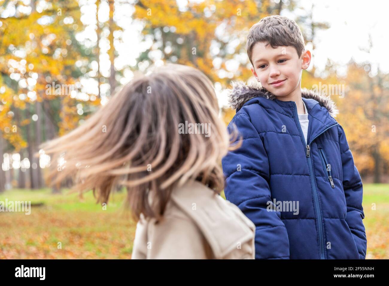 Bruder sieht Schwester spielen, während sie im Wald steht Stockfoto