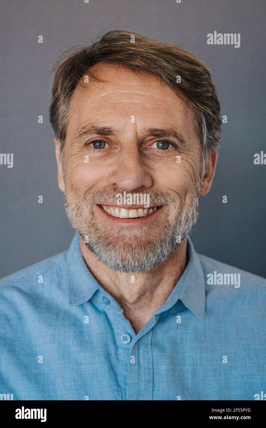 Lächelnder Mann mit Bart vor grauem Hintergrund Stockfoto