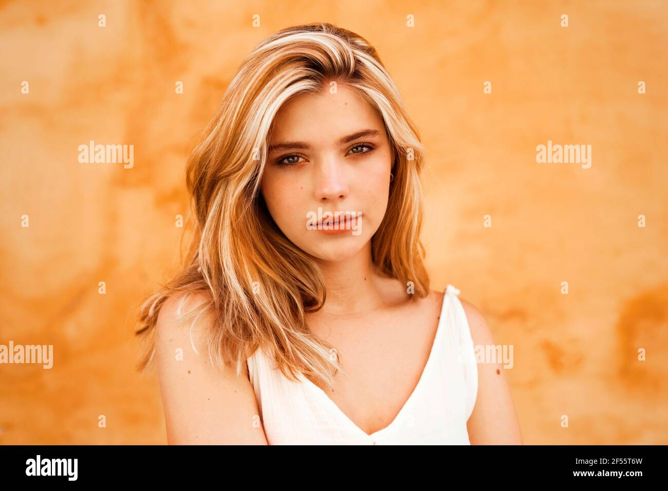 Junge blonde Frau gegen gelbe Wand Stockfoto