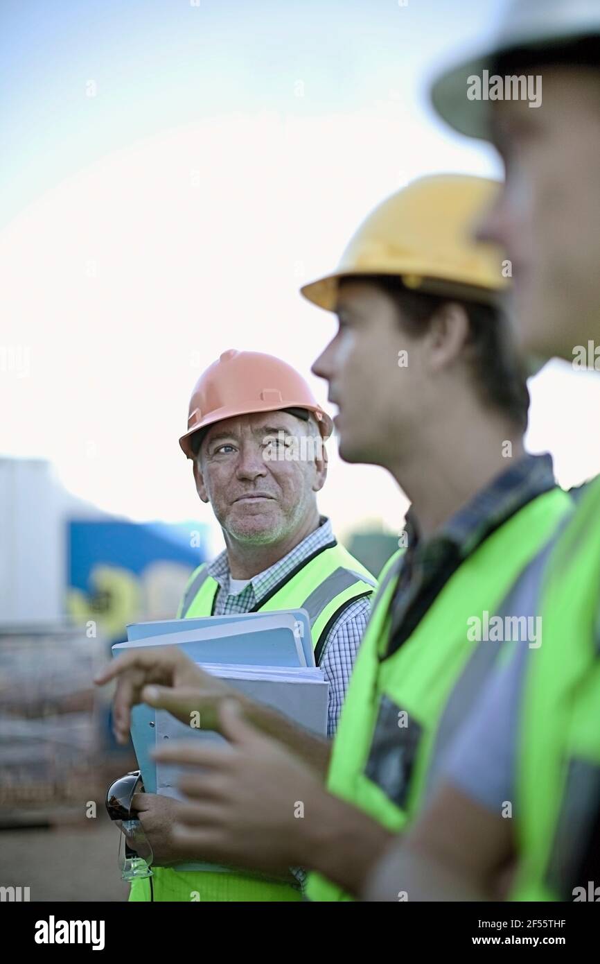 Drei männliche Bauarbeiter sprechen im Freien Stockfoto