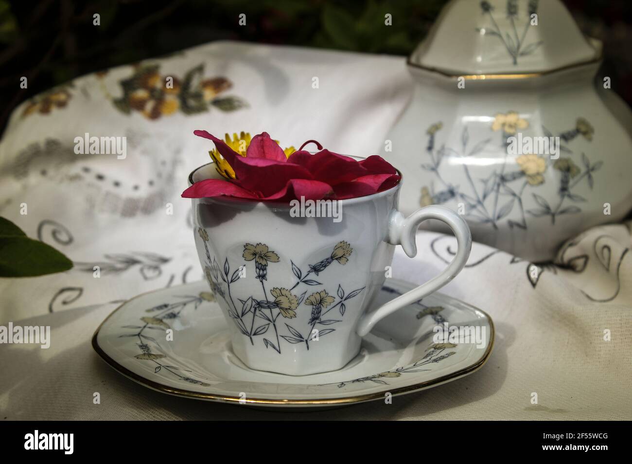 Splendid Kräutertee-Set bestehend aus einer Tasse und Zucker Schüssel auf einem alten bestickten Tischdecke platziert, in der Tasse Blumen, alle im Vintage-Ton Stockfoto