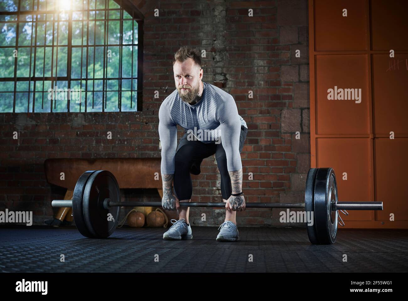 Aktiver männlicher Athlet, der während des Trainings im Fitnessstudio eine Langhantel hebt Stockfoto