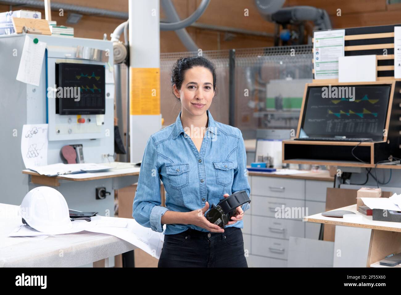 Geschäftsfrau mit Ohrenschützern, während sie in der Fabrik steht Stockfoto