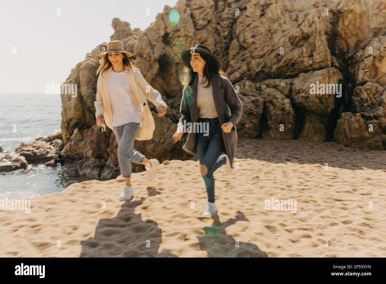 Lächelnde Schwestern laufen am Strand auf Sand Stockfoto