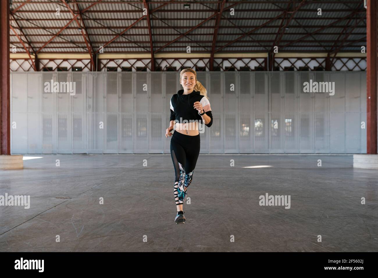 Lächelnde Sportlerin, die während des Trainings im Fitnessclub läuft Stockfoto