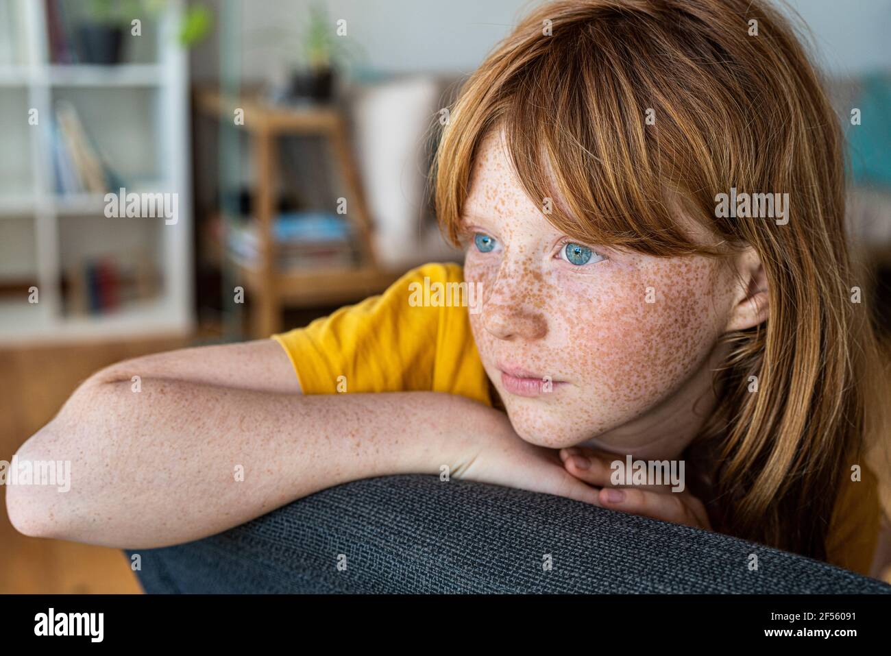 Betrachten Rotschopf Mädchen auf Stuhl zu Hause sitzen Stockfoto