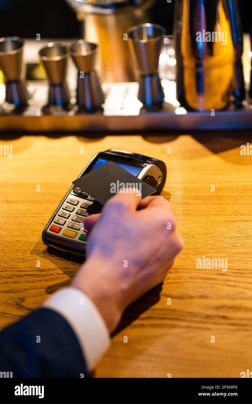 Mann mit Kreditkarte in der Nähe des Lesers für die Zahlung im Café Stockfoto