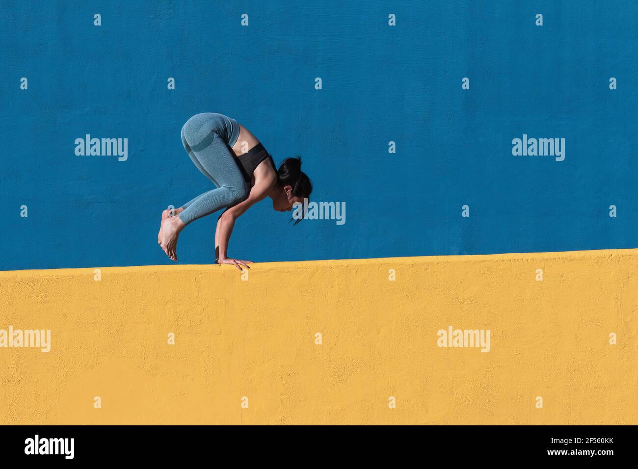 Eine starke Frau, die an einer Wand einen Handstand macht Stockfoto