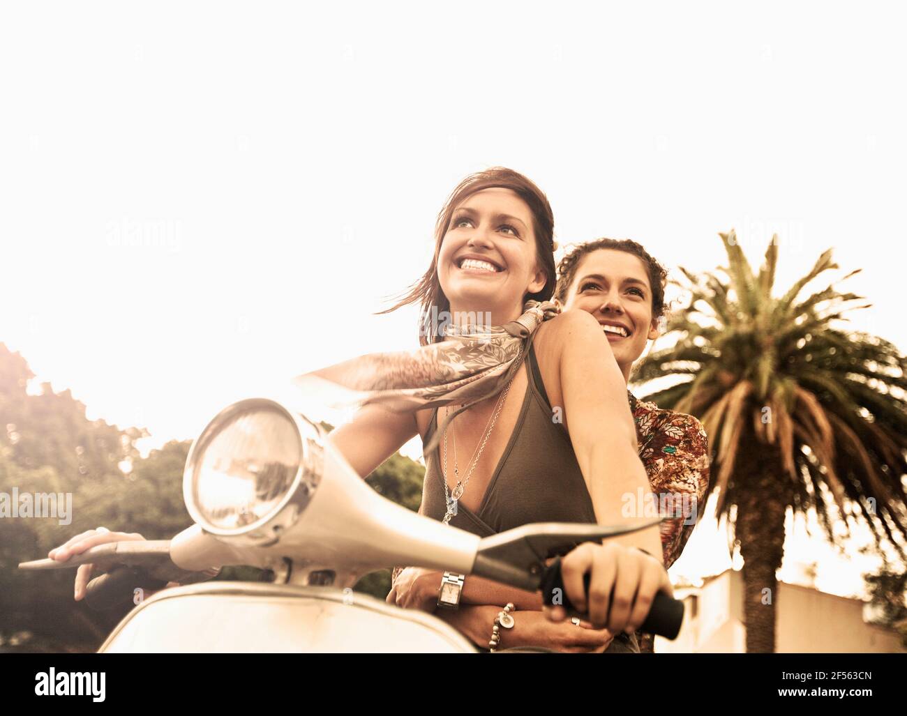 Lächelnde Frau genießt Roller fahren mit Freund Stockfoto