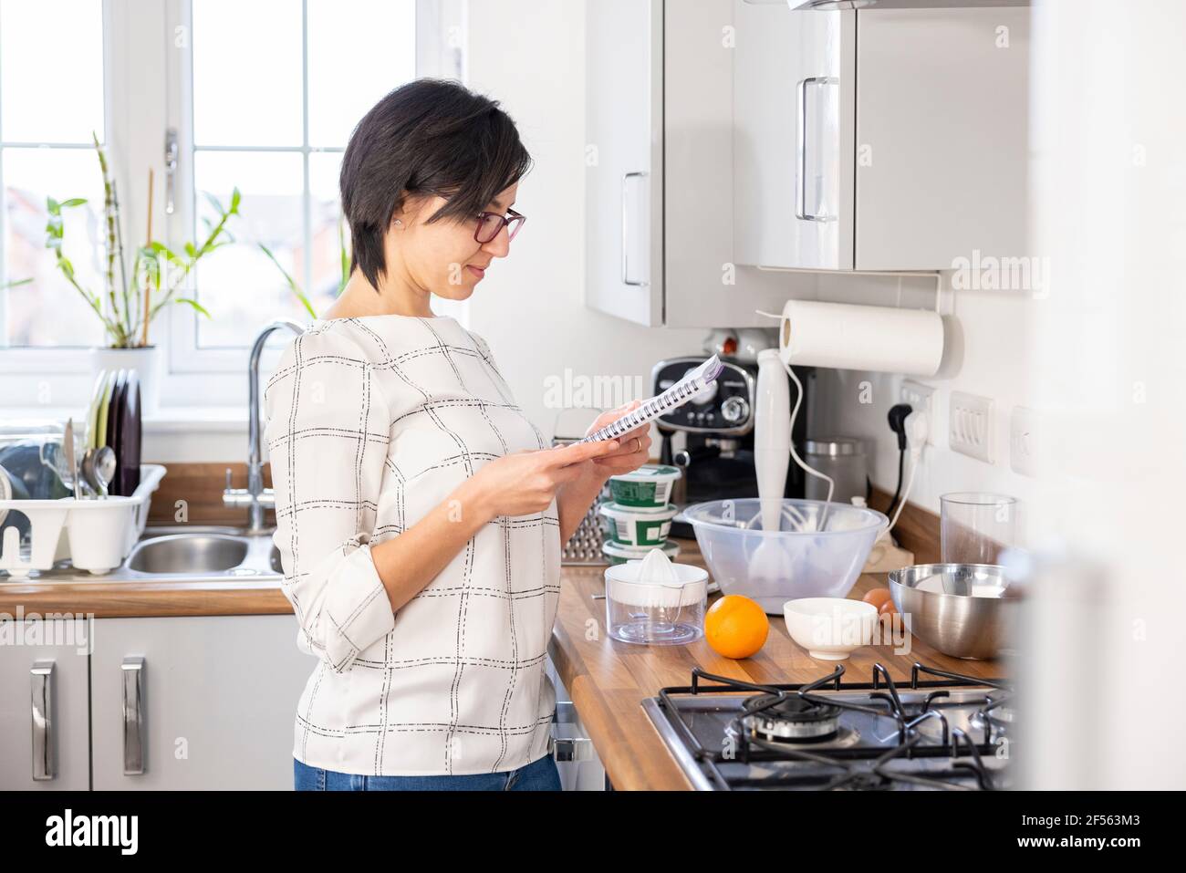 Frau liest ein Rezept, bevor sie zu Hause Kuchen backen Stockfoto